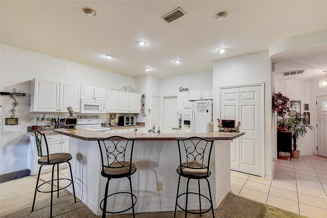 14985 Alan Ct, Largo, FL 33771 - kitchen featuring white appliances, a kitchen breakfast bar, white cabinetry, dark countertops, and a kitchen island