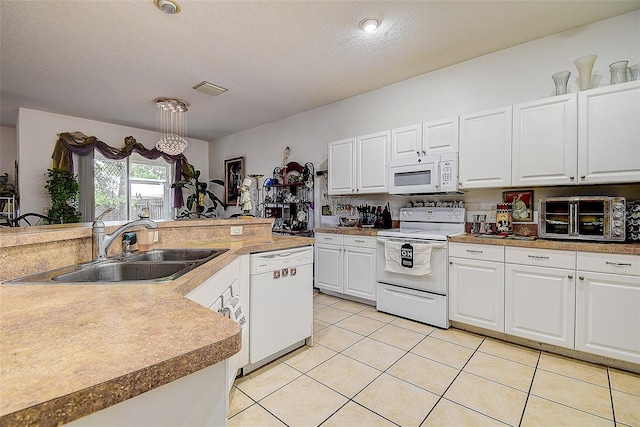 14985 Alan Ct, Largo, FL 33771 - kitchen with white appliances, a sink, white cabinetry, light tile patterned floors, and a textured ceiling