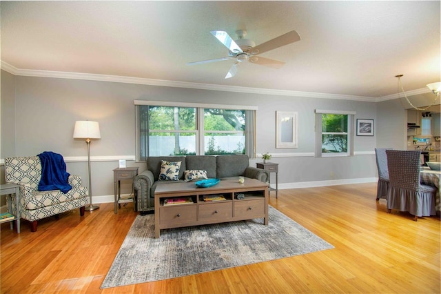 living area with wood finished floors, a ceiling fan, baseboards, and ornamental molding
