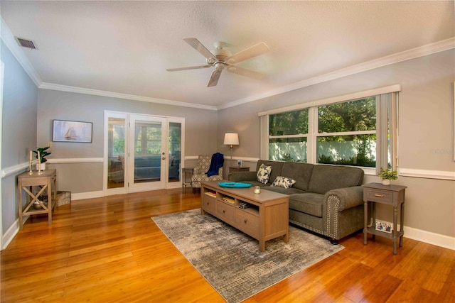 living area featuring plenty of natural light, ceiling fan, light wood finished floors, and crown molding