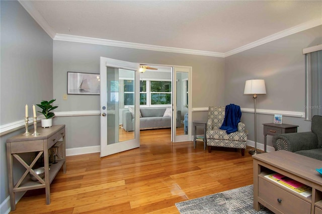 sitting room with ornamental molding, light wood finished floors, baseboards, and french doors