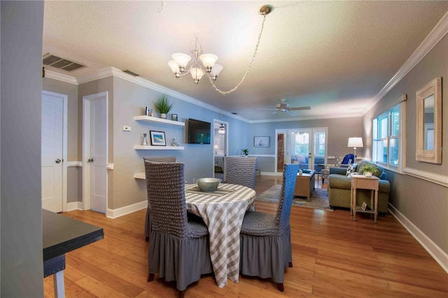 dining area featuring a chandelier, ceiling fan, light wood-type flooring, crown molding, and baseboards