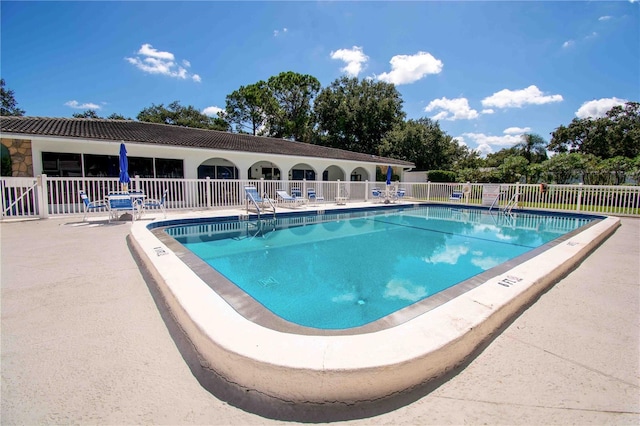 community pool with fence and a patio
