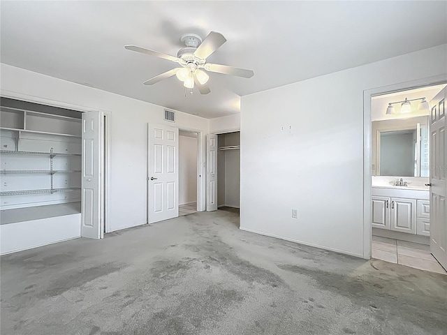 904 Desert Hills Dr, Sun City Center, FL 33573 - unfurnished bedroom featuring multiple closets, ceiling fan, ensuite bathroom, and light carpet