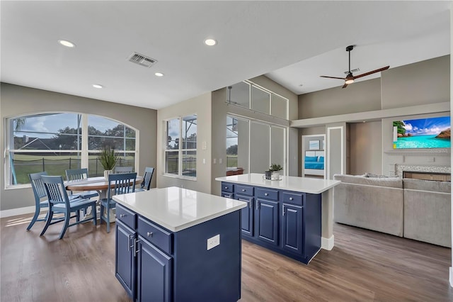 1530 The Oaks Blvd, Kissimmee, FL 34746 - kitchen with blue cabinetry, a kitchen island, wood finished floors, ceiling fan, and recessed lighting