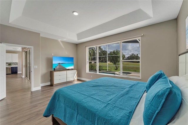 1530 The Oaks Blvd, Kissimmee, FL 34746 - bedroom featuring a tray ceiling, wood finished floors, and baseboards