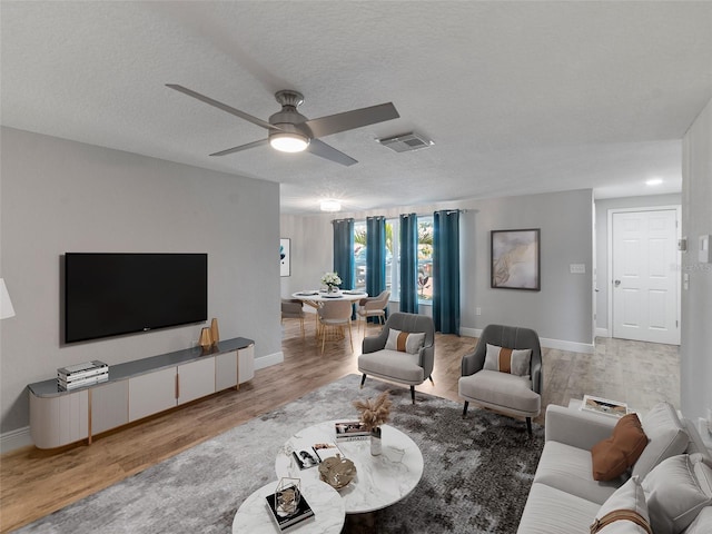 4238 Glissade Dr, New Port Richey, FL 34652 - living room featuring light wood-style flooring, baseboards, ceiling fan, and a textured ceiling