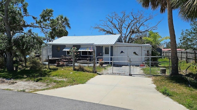 view of front of property with a gate, driveway, metal roof, and central air condition unit