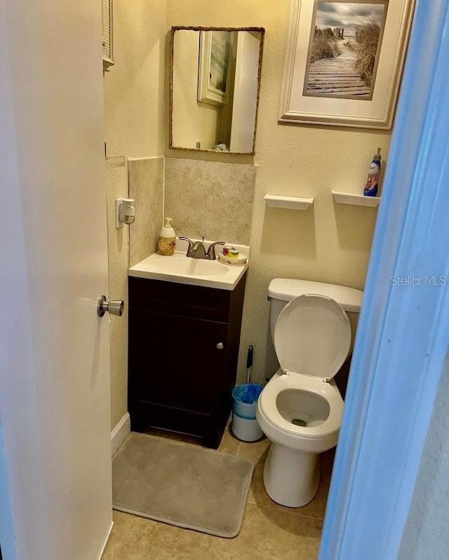 half bathroom featuring vanity, toilet, and tile patterned floors