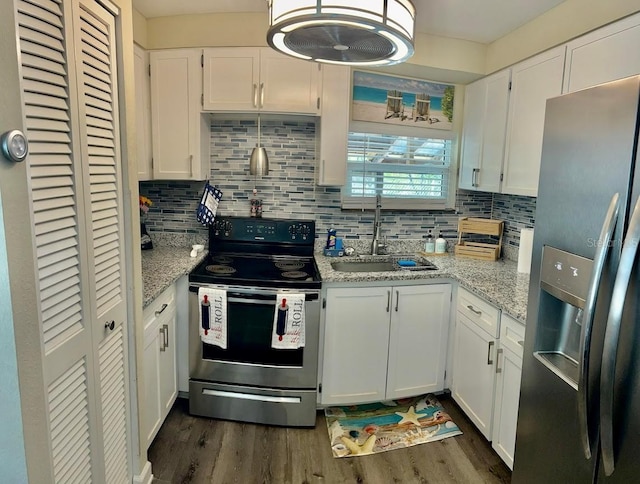 kitchen with appliances with stainless steel finishes, a sink, dark wood finished floors, white cabinetry, and decorative backsplash