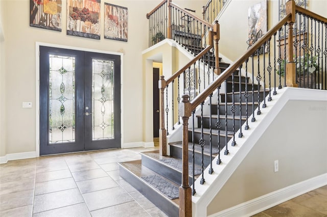 foyer featuring french doors, baseboards, a high ceiling, and stairs