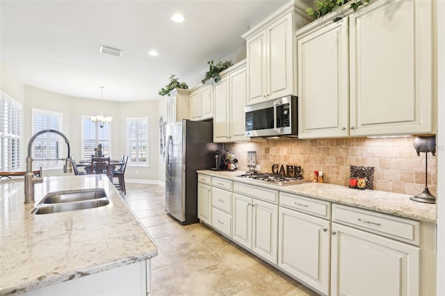 kitchen featuring stainless steel appliances, a sink, a chandelier, tasteful backsplash, and recessed lighting
