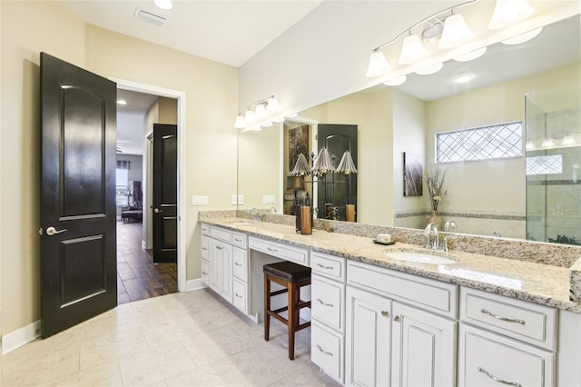 full bath with double vanity, tiled shower, and baseboards