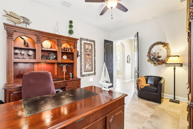 office space featuring ceiling fan, arched walkways, light tile patterned flooring, and baseboards
