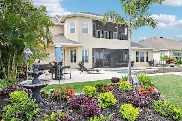 rear view of property featuring a sunroom, stucco siding, a patio area, and an outdoor pool