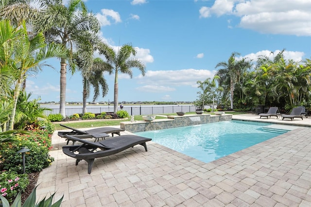 view of pool with a patio area, fence, and a water view