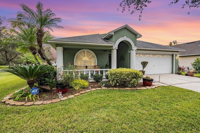 ranch-style home featuring driveway, an attached garage, stucco siding, and a front lawn