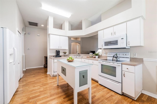 kitchen featuring white appliances, light countertops, white cabinets, light wood-type flooring, and a sink