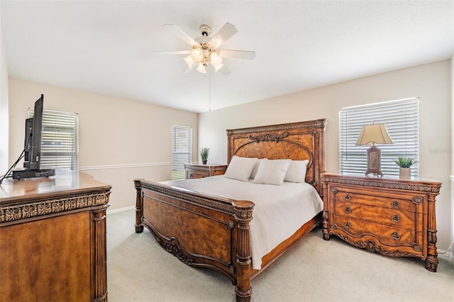 bedroom with light colored carpet, multiple windows, baseboards, and ceiling fan