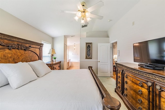 bedroom featuring light carpet, lofted ceiling, ensuite bath, and a ceiling fan
