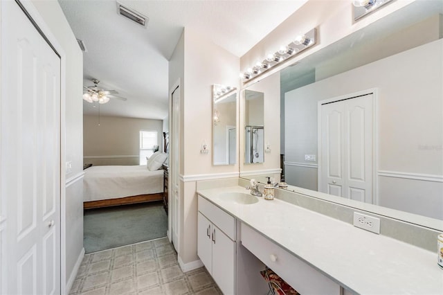 ensuite bathroom featuring a ceiling fan, vanity, tile patterned floors, and baseboards