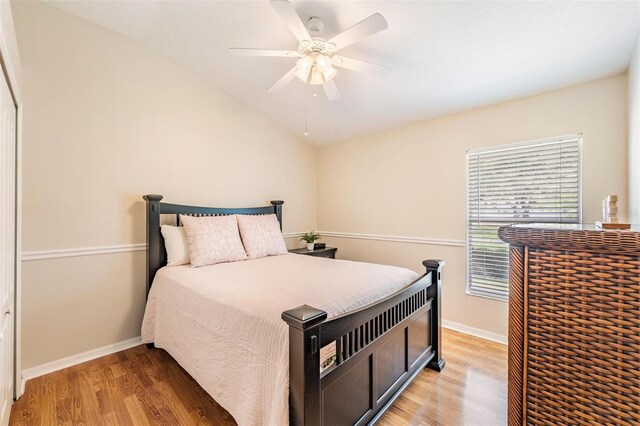 bedroom with light wood-style flooring, baseboards, vaulted ceiling, and a ceiling fan