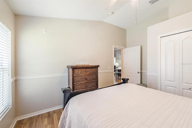 bedroom with wood finished floors, a closet, lofted ceiling, baseboards, and ceiling fan