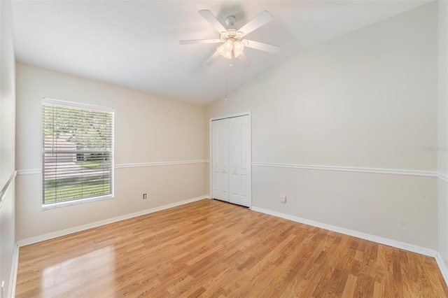 empty room with lofted ceiling, light wood-type flooring, baseboards, and a ceiling fan