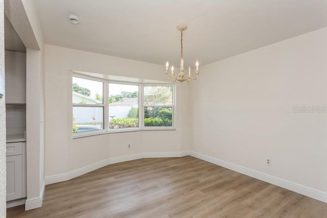 empty room featuring a chandelier, baseboards, and healthy amount of natural light