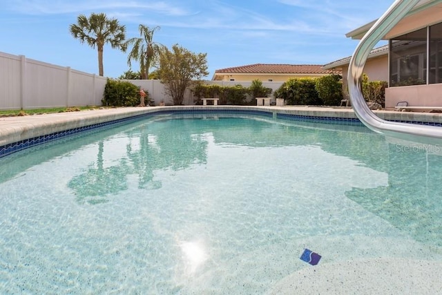 view of swimming pool with a fenced backyard and a water slide