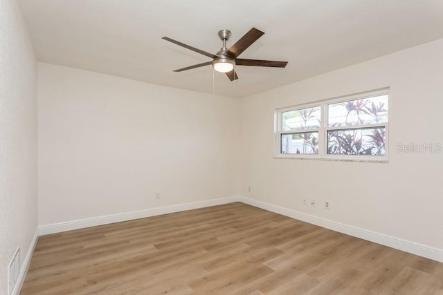 spare room featuring a ceiling fan, light wood-style flooring, and baseboards