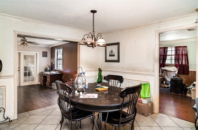 504 Casas Bonitas Dr, Nokomis, FL 34275 - dining area with light tile patterned floors, a chandelier, crown molding, wainscoting, and a ceiling fan