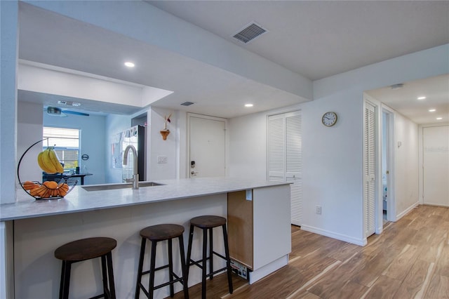 2870 Rampart Cir, Clearwater, FL 33761 - kitchen featuring a sink, wood finished floors, a kitchen bar, recessed lighting, and baseboards