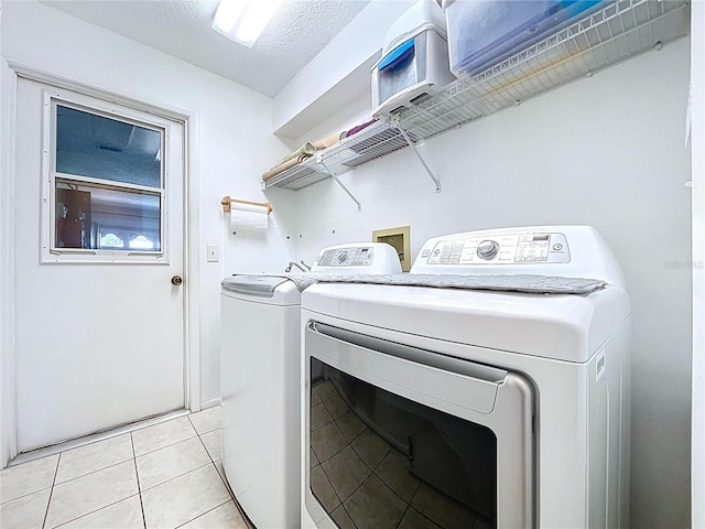 10520 Tapestry Dr, Port Richey, FL 34668 - laundry area featuring washing machine and dryer, light tile patterned floors, and a textured ceiling