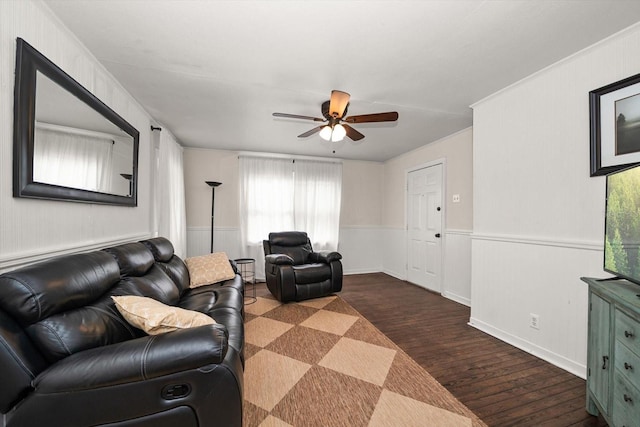 living area with wood finished floors, a ceiling fan, and wainscoting