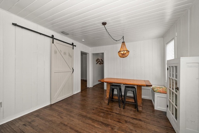 dining area with a barn door and dark wood finished floors