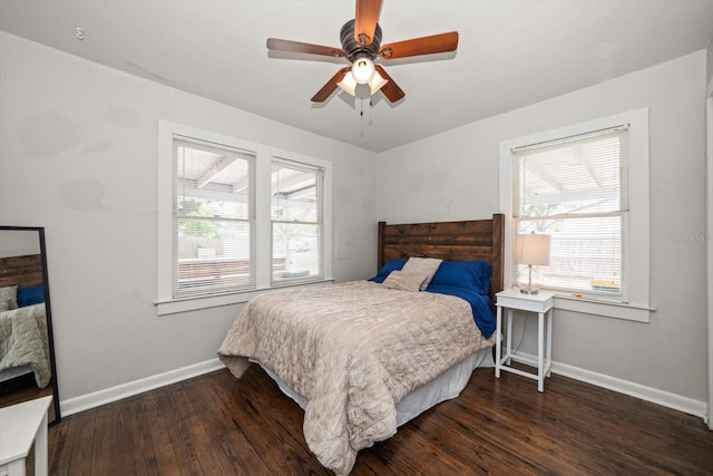 bedroom featuring baseboards, multiple windows, wood finished floors, and ceiling fan