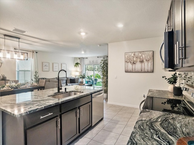 17012 Oval Rum Dr, Wimauma, FL 33598 - kitchen featuring stainless steel appliances, open floor plan, light stone countertops, an island with sink, and light tile patterned floors