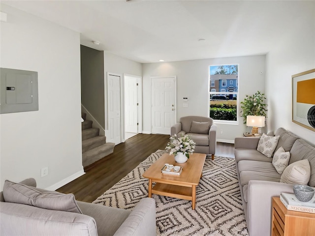 living area featuring electric panel, stairs, wood finished floors, and baseboards