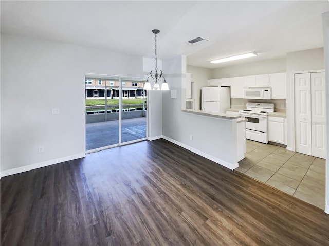kitchen featuring white appliances, light countertops, a chandelier, white cabinetry, and a peninsula