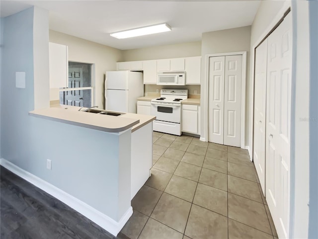 kitchen featuring white appliances, light countertops, a sink, and white cabinetry