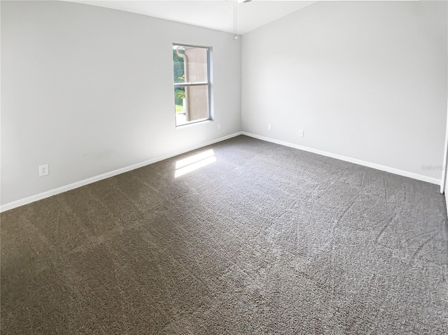unfurnished room with dark carpet and baseboards