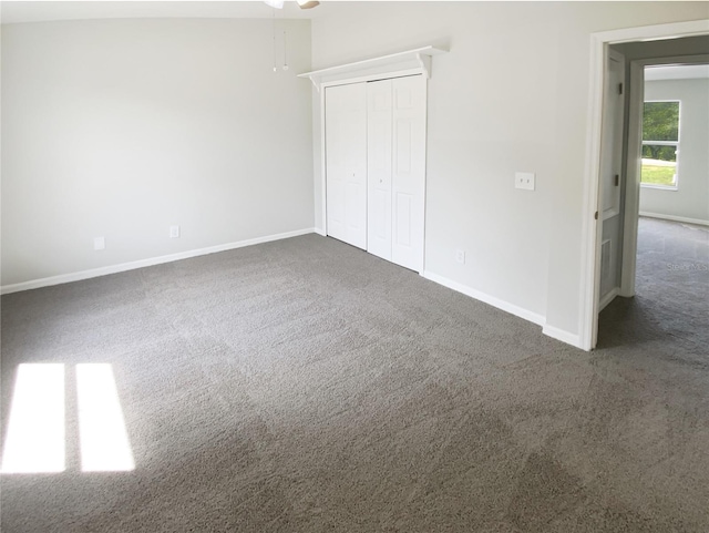 unfurnished bedroom featuring dark carpet, baseboards, and a closet