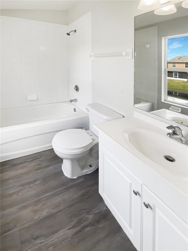 bathroom featuring toilet, washtub / shower combination, vanity, and wood finished floors