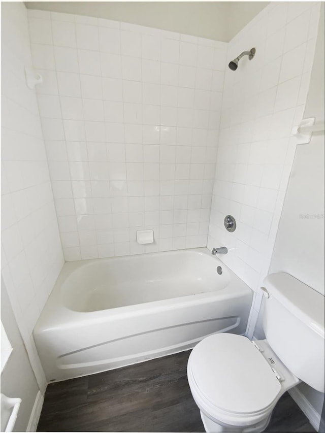 bathroom with toilet, wood finished floors, and  shower combination