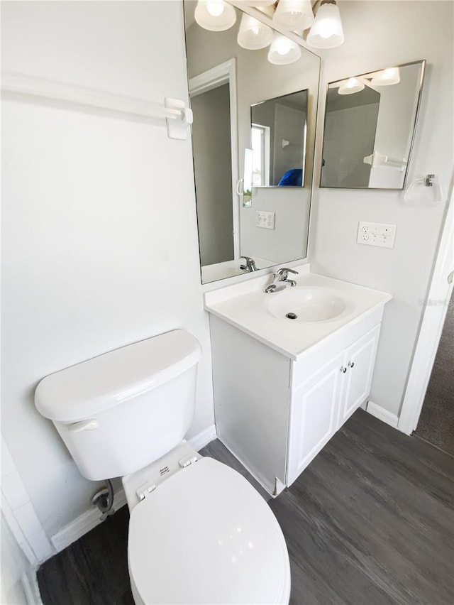 bathroom with vanity, wood finished floors, toilet, and baseboards