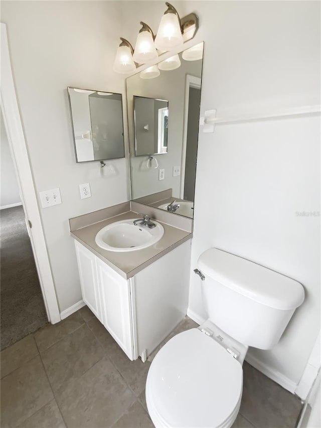 bathroom with toilet, vanity, tile patterned floors, and baseboards