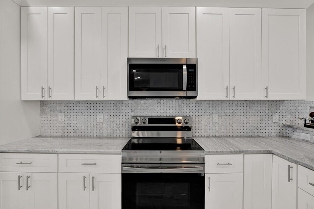 4071 45th Ave N, Saint Petersburg, FL 33714 - kitchen with stainless steel appliances, backsplash, white cabinetry, and light stone countertops