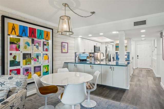 7564 Bayshore Dr Unit 302, Treasure Island, FL 33706 - kitchen featuring dark countertops, crown molding, appliances with stainless steel finishes, dark wood-style floors, and a peninsula