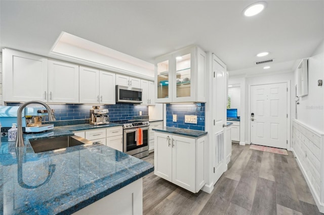 7564 Bayshore Dr Unit 302, Treasure Island, FL 33706 - kitchen featuring appliances with stainless steel finishes, a sink, white cabinetry, dark stone countertops, and recessed lighting